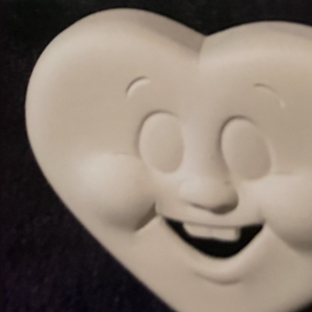 Heart face, up right, teeth, eyes open, number 68, unpainted bisque on black velvet
